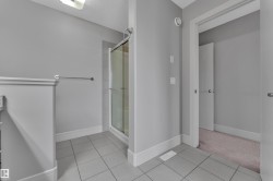 Bathroom featuring a glass-enclosed shower, neutral wall tones, and tiled flooring - 