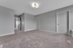 Spacious room featuring neutral grey walls and plush grey carpeting - 