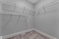 Walk-in closet featuring wire shelving, gray painted walls, white baseboards, and brown carpet flooring - 