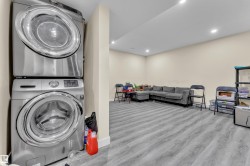 Laundry area featuring a stacked washer and dryer, recessed ceiling lighting, light-toned walls, and wood-finish flooring - 