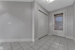 Entryway featuring light gray ceramic tile flooring, a white paneled door with horizontal blinds, and a built-in closet with bifold doors - 