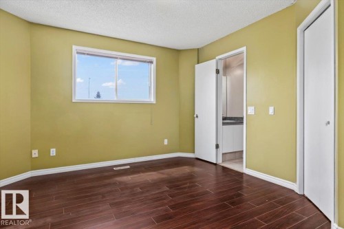 Room featuring wood-finish flooring, a bright window, and a crisp white ceiling - 8103 154 Avenue, Edmonton, AB 