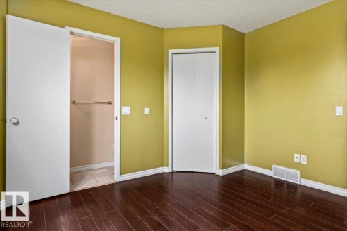 Room featuring wood-finish flooring, white baseboards, and a neutral wall color - 8103 154 Avenue, Edmonton, AB 