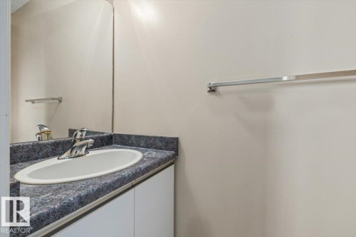 Vanity with an integrated oval sink, dark speckled countertop, and chrome faucet - 8103 154 Avenue, Edmonton, AB 