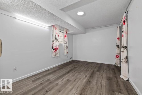 Room featuring wood-finish flooring, white walls, and a recessed ceiling light - 8103 154 Avenue, Edmonton, AB 