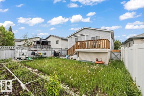 Rear exterior featuring a wood deck with railing, siding facade, and a fenced yard - 8103 154 Avenue, Edmonton, AB 