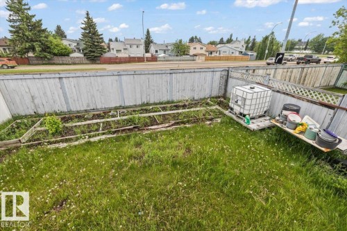Fenced backyard with established garden beds and a grassy area - 8103 154 Avenue, Edmonton, AB 