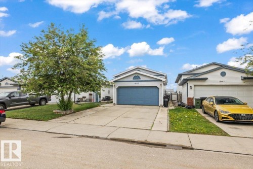 Single-story residence featuring white siding and a blue garage door - 8103 154 Avenue, Edmonton, AB 