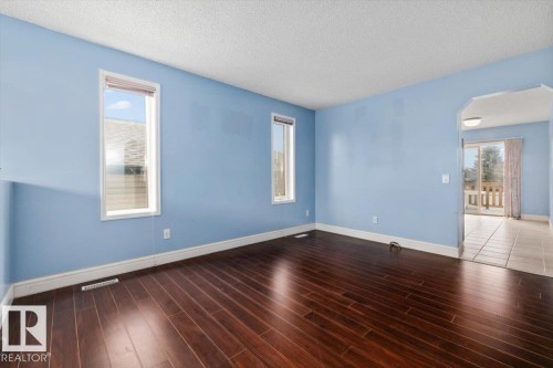 Spacious room featuring rich wood-finish flooring, light blue walls, and white trim - 8103 154 Avenue, Edmonton, AB 