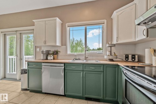 Kitchen featuring a double basin sink, white subway tile backsplash, and wood-finish countertops - 14 53122 Rge Road 14, Rural Parkland County, AB 