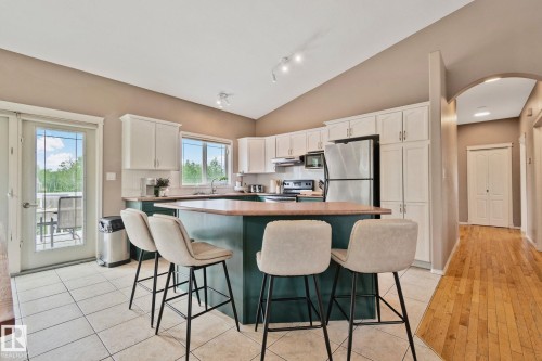 Kitchen featuring a central island with countertop seating, white cabinetry, and stainless steel appliances - 14 53122 Rge Road 14, Rural Parkland County, AB 