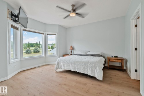 Spacious room featuring a bay window, wood-finish flooring, and a ceiling fan with integrated lighting - 14 53122 Rge Road 14, Rural Parkland County, AB 