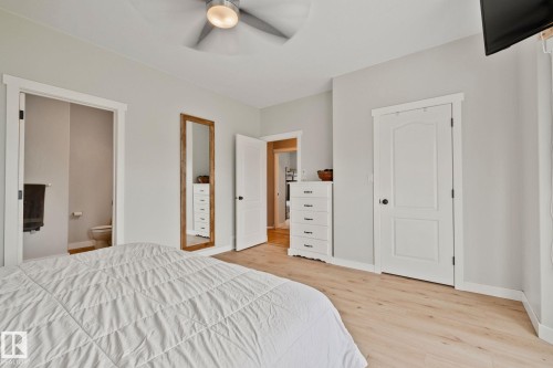 Bedroom featuring light wood-finish flooring, a ceiling fan with integrated lighting, and a white two-panel interior door - 14 53122 Rge Road 14, Rural Parkland County, AB 