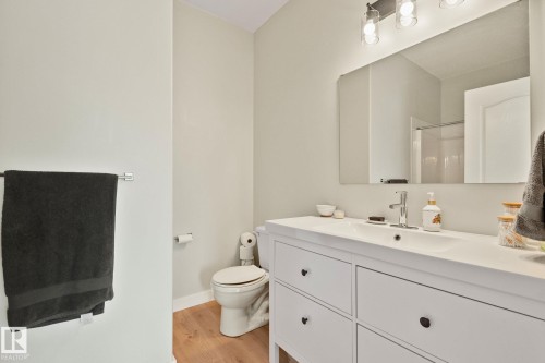 Bathroom featuring a white vanity with integrated sink, chrome faucet, and wood-finish flooring - 14 53122 Rge Road 14, Rural Parkland County, AB 