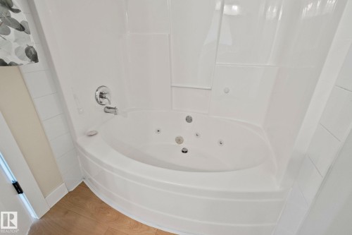 White jetted soaking tub with a chrome faucet and showerhead, surrounded by a white tile-effect enclosure - 14 53122 Rge Road 14, Rural Parkland County, AB 