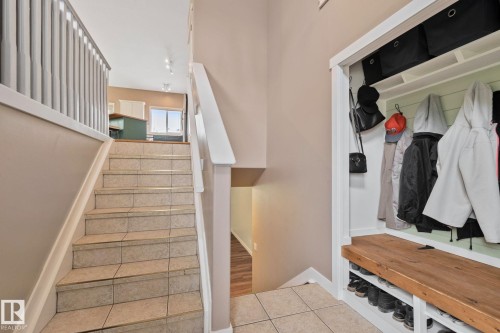 Tiled staircase with white railings, built-in mudroom bench with wood-finish top, integrated shoe storage, and coat hooks - 14 53122 Rge Road 14, Rural Parkland County, AB 
