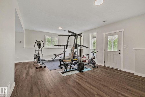 Spacious room featuring wood-finish flooring, light-toned walls, recessed lighting, and a white paneled door with a clear glass insert - 14 53122 Rge Road 14, Rural Parkland County, AB 