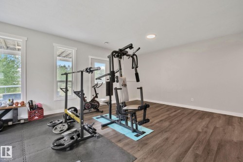 Spacious room featuring wood-finish flooring, light grey walls, and two large windows with white trim - 14 53122 Rge Road 14, Rural Parkland County, AB 