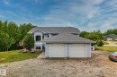 Light blue siding home featuring a two-car attached garage with arch-top doors, a multi-pane bay window, and a dark shingle roof - 14 53122 Rge Road 14, Rural Parkland County, AB 