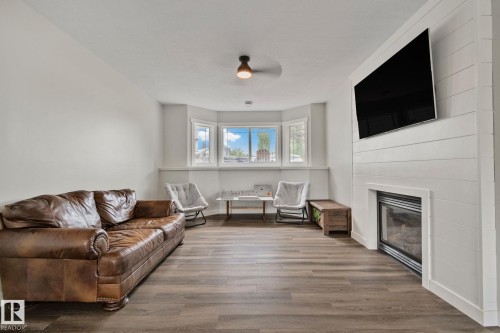 Spacious living area featuring wood-finish flooring, a contemporary fireplace with a shiplap surround, and a bay window - 14 53122 Rge Road 14, Rural Parkland County, AB 