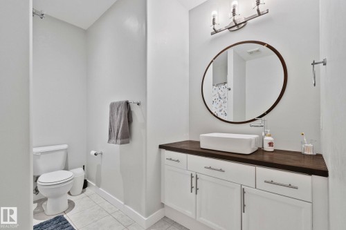 Bathroom featuring a white vanity with wood-finish countertop, vessel sink, and an oval framed mirror - 14 53122 Rge Road 14, Rural Parkland County, AB 