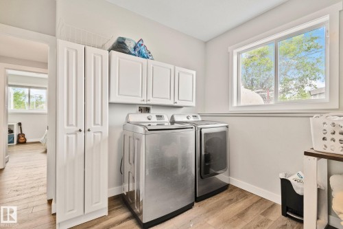 Dedicated laundry area featuring wood-finish flooring, white cabinetry, and a double-door storage cabinet - 14 53122 Rge Road 14, Rural Parkland County, AB 