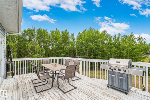 Exterior deck featuring wood-finish flooring, white railing, and a light blue siding exterior - 14 53122 Rge Road 14, Rural Parkland County, AB 