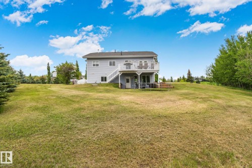 Expansive exterior featuring a light gray siding, a large upper-level deck, a ground-level patio, and a vast grassy area - 14 53122 Rge Road 14, Rural Parkland County, AB 