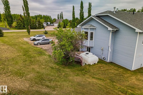 Light blue siding exterior featuring a bay window, asphalt shingle roof, and established landscaping - 14 53122 Rge Road 14, Rural Parkland County, AB 