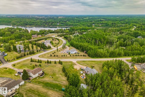 Aerial perspective showcasing a residential area surrounded by abundant mature trees and a prominent body of water in the background - 14 53122 Rge Road 14, Rural Parkland County, AB 