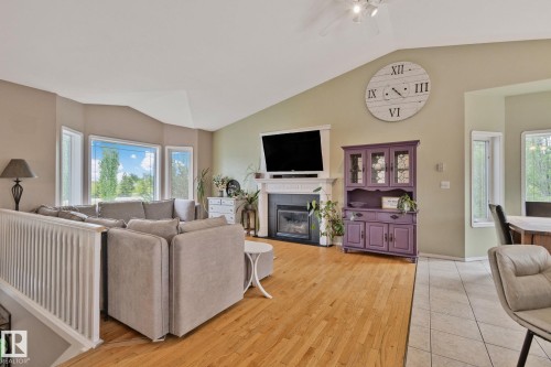 Vaulted ceiling living area featuring hardwood-finish flooring, a prominent fireplace with a white mantel, and a bay window configuration - 14 53122 Rge Road 14, Rural Parkland County, AB 