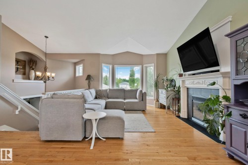 Open living area featuring wood-finish flooring, a fireplace with a white mantel and tile surround, and large bay windows - 14 53122 Rge Road 14, Rural Parkland County, AB 