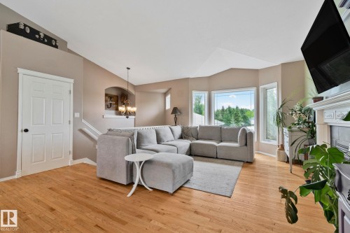 Living area featuring wood-finish flooring, a bay window configuration, a detailed fireplace mantel, a multi-panel door, and an arched entry - 14 53122 Rge Road 14, Rural Parkland County, AB 