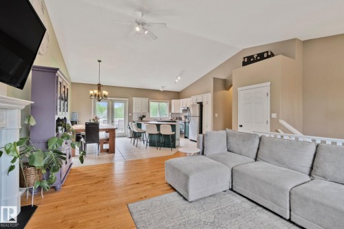 Open-concept living space featuring wood-finish flooring, vaulted ceilings, and a white fireplace surround - 14 53122 Rge Road 14, Rural Parkland County, AB 