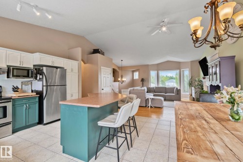 Open-concept living area with vaulted ceilings, featuring a kitchen island with seating, stainless steel appliances, and a bay window in the living room - 14 53122 Rge Road 14, Rural Parkland County, AB 