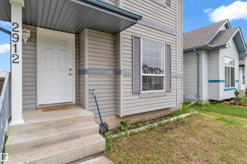 Exterior featuring light gray siding, white front door, dark gray shutters, white trim, and concrete steps - 2912 31 Street, Edmonton, AB 