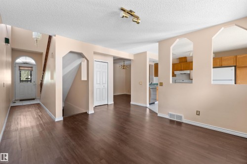 Spacious living area featuring wood-finish flooring, a neutral color palette, and multiple arched wall openings - 5 20 Deerbourne Drive, St. Albert, AB 