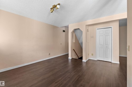 Spacious room featuring wood-finish flooring, light neutral walls, and white baseboards - 5 20 Deerbourne Drive, St. Albert, AB 