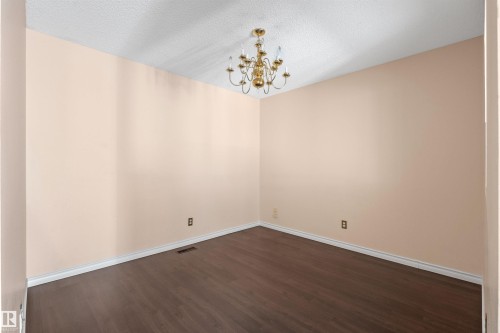 Spacious room featuring wood-finish flooring, light-toned walls, white baseboards, and a brass chandelier - 5 20 Deerbourne Drive, St. Albert, AB 