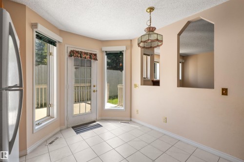 Bright eat-in kitchen area featuring white square tile flooring, a glass-paneled door, and two arched wall openings - 5 20 Deerbourne Drive, St. Albert, AB 