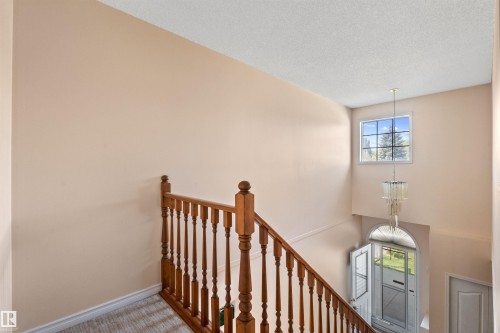 Two-story foyer with a natural wood staircase, a crystal chandelier, and an arched transom window over the entry door - 5 20 Deerbourne Drive, St. Albert, AB 