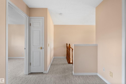 Upper-level hallway featuring light peach walls, white trim, and textured gray carpeting - 5 20 Deerbourne Drive, St. Albert, AB 