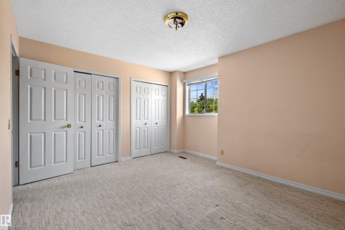 Carpeted room featuring multiple panel doors, a ceiling-mounted light fixture, and a window with exterior visibility - 5 20 Deerbourne Drive, St. Albert, AB 