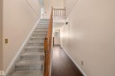 Foyer featuring a carpeted staircase with a wood-finish handrail, wood-finish flooring, and light-toned walls - 5 20 Deerbourne Drive, St. Albert, AB 