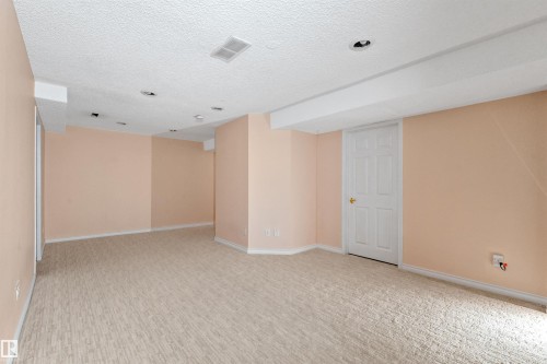 Spacious finished room featuring textured carpeting, neutral wall colors, recessed ceiling lighting, and a paneled door - 5 20 Deerbourne Drive, St. Albert, AB 
