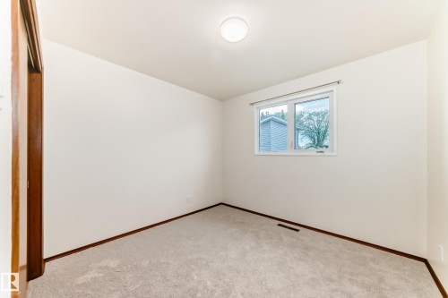 Carpeted room featuring white walls, a single window, a ceiling-mounted light fixture, and wood-finish trim - 12022 62 Street, Edmonton, AB 