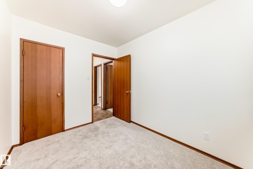 Carpeted room with white walls, wood-finish interior doors, and matching wood-finish baseboards - 12022 62 Street, Edmonton, AB 