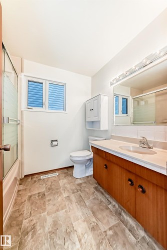 Bathroom featuring a single vanity with wood-finish cabinetry, a neutral countertop, and a built-in sink - 12022 62 Street, Edmonton, AB 