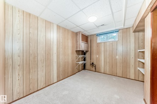 Finished room featuring light wood-panel walls, neutral carpeting, and a drop ceiling with recessed lighting - 12022 62 Street, Edmonton, AB 