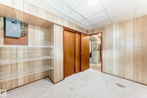 Finished lower level space featuring wood-finish wall paneling, white wire shelving, wood doors, and textured ceiling panels - 12022 62 Street, Edmonton, AB 